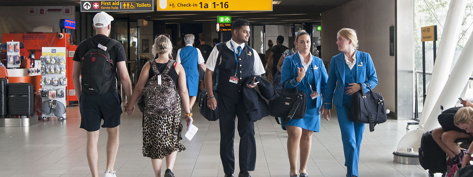 Steward, stewardessen en toeristen op luchthaven. 